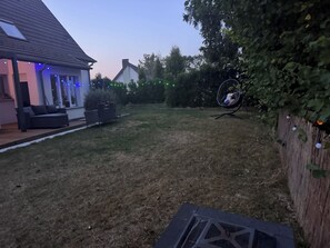A residential backyard with a patio, a swing chair, and a wooden fence.