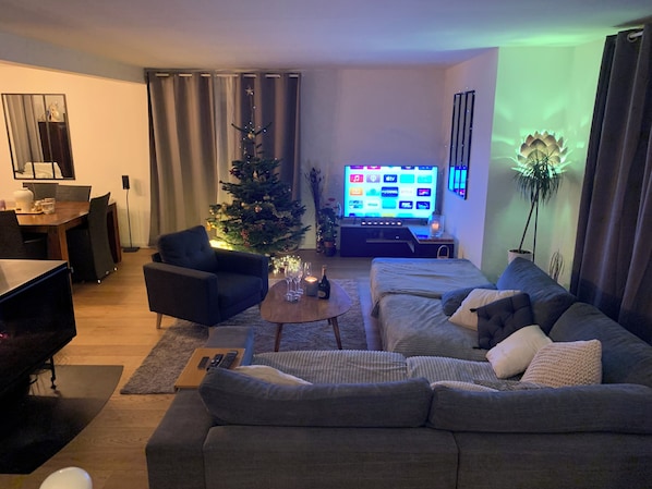 A living room with a sofa, armchair, coffee table, and a Christmas tree.