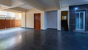 Un hall d’entrée spacieux, doté d’un sol ciré, d’une porte en bois et d’un escalier menant à un espace sombre carrelé.