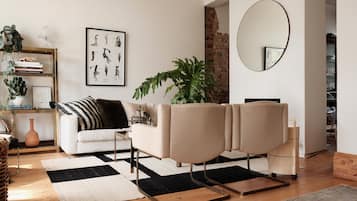 A modern living room with a sofa, a coffee table, a potted plant, a framed picture on the wall, and a mirror.