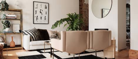 A modern living room with a sofa, a coffee table, a potted plant, a framed picture on the wall, and a mirror.