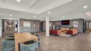 A spacious lobby with a reception desk, seating area, and a Netflix sign. - Modern 1BR CIN Suite | Pool, Gym (Cincinnati)