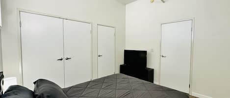 A bedroom with a bed, two wardrobes, a television, and a ceiling light fixture.