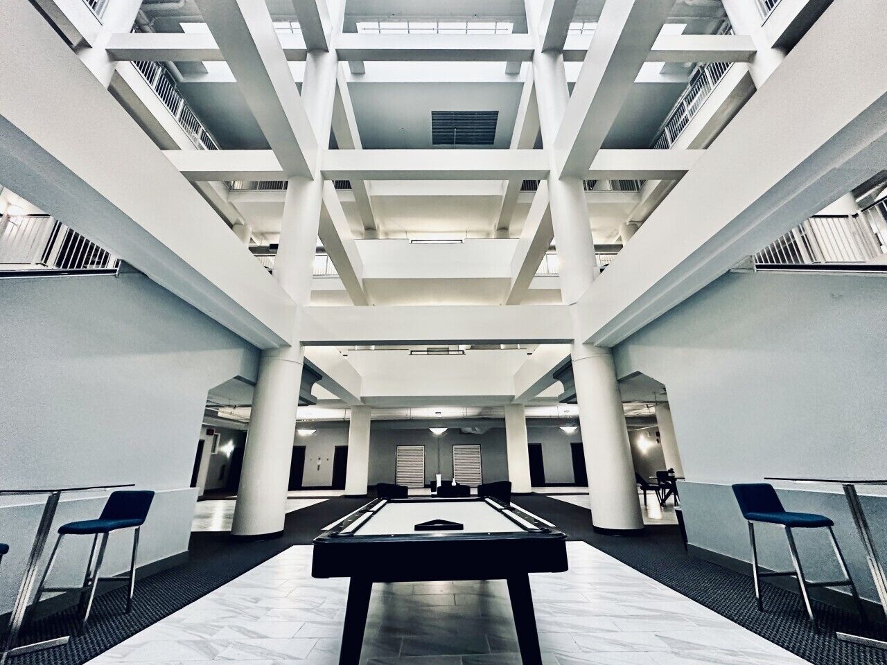Eine großzügige Lobby mit einem zentral platzierten Billardtisch, hohen Decken und modernem architektonischen Design.