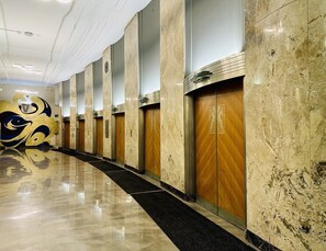 Ein Hotelgang mit Marmorwänden, Holztüren und einem spiegelnden Boden.