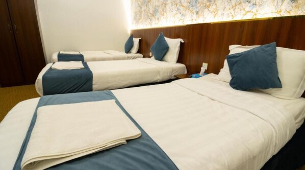 Ein Hotelzimmer mit zwei Betten, jedes mit einem blauen Kissen und einer weißen Decke.