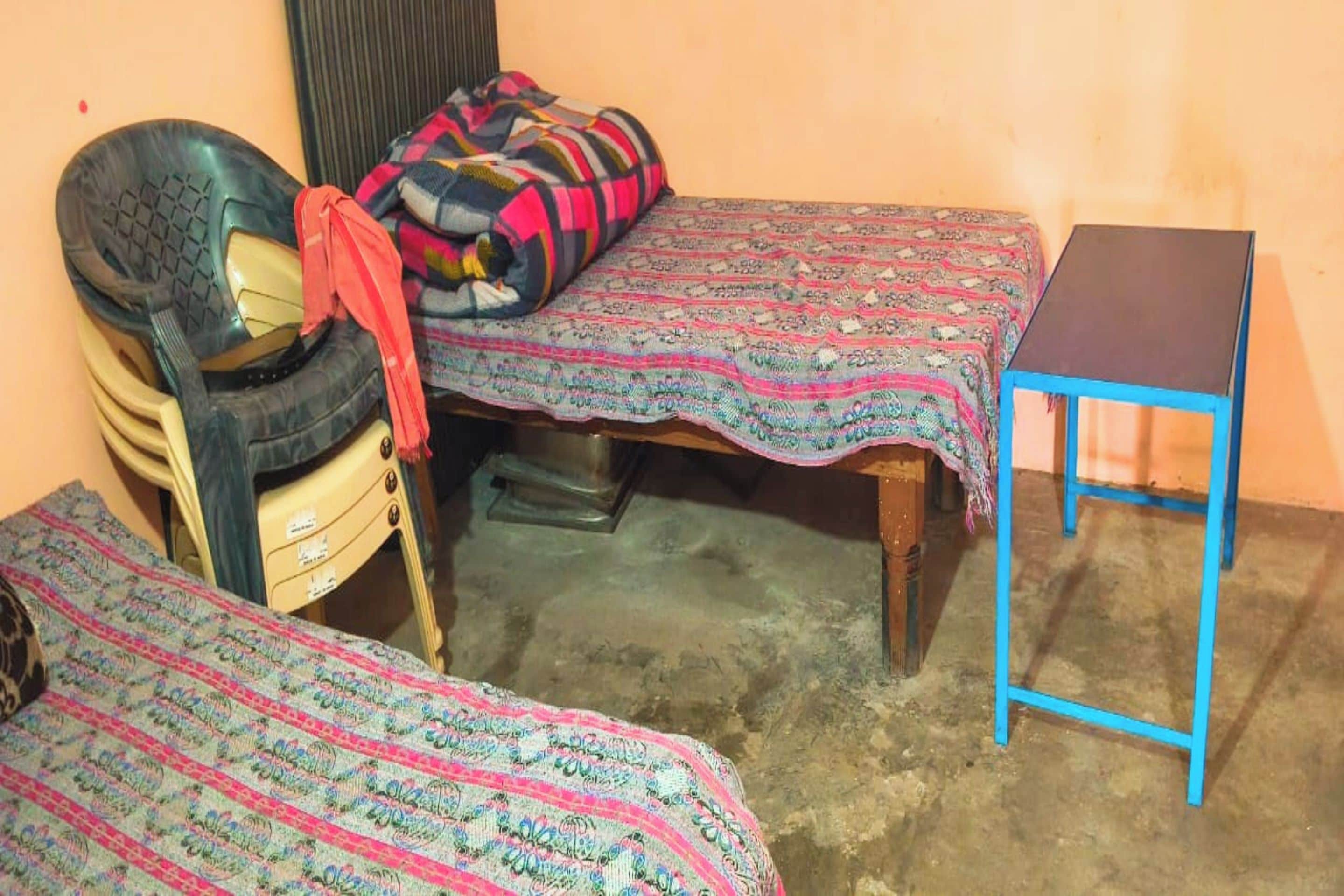 A small room with two beds, a chair, and a table.