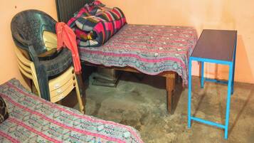 A small room with two beds, a chair, and a table.