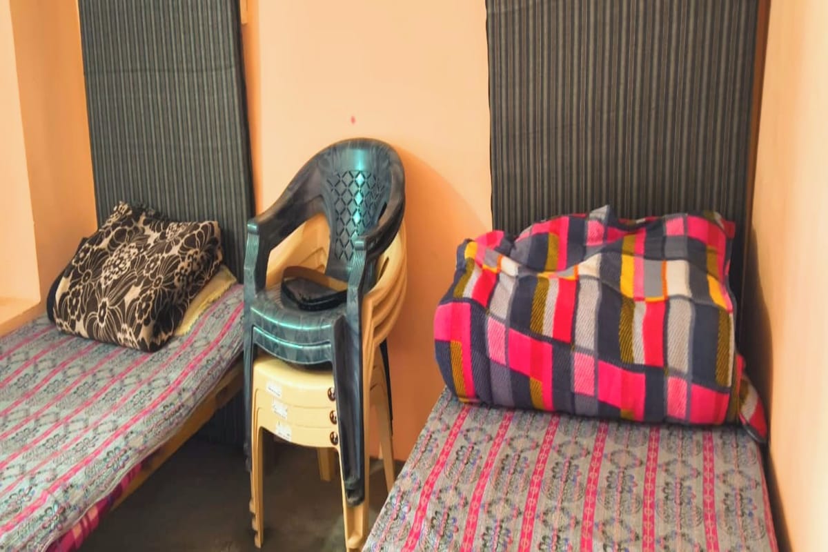 Una habitación pequeña con dos camas individuales, una silla y una almohada.