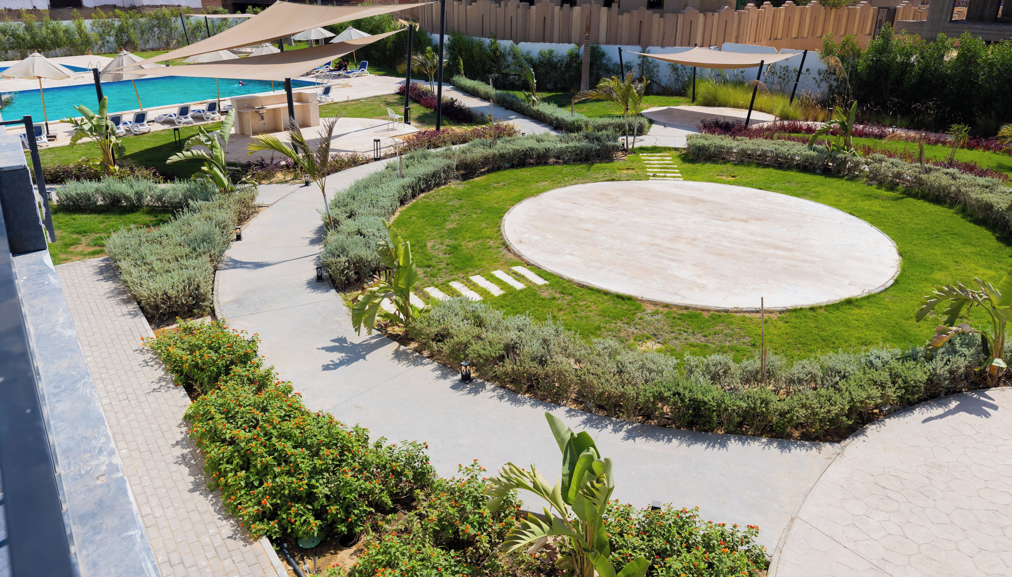 Un espace extérieur aménagé avec une piscine, des chaises longues et un jardin circulaire.