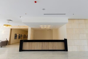 Un vestíbulo amplio con una recepción, una araña y una pared decorada con obras de arte enmarcadas.