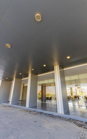 A modern building entrance with glass doors, a tiled floor, and recessed lighting. - SettleInn Joud Hotel (Cairo)