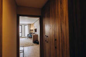 Habitación de hotel con un armario de madera, un escritorio, una silla y vistas al pasillo.