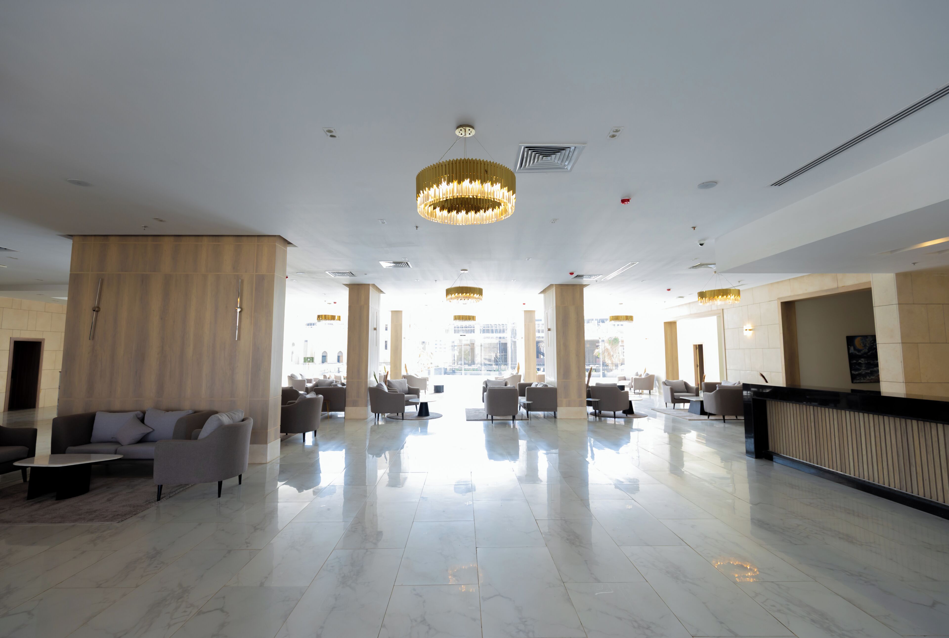 Un hall d’entrée spacieux, doté d’un sol en marbre, de plusieurs espaces aménagés pour s’asseoir et de grands lustres.