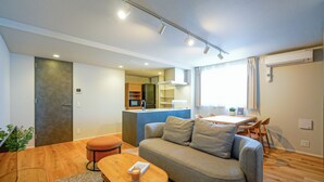 Een moderne woonkamer met een bank, een kleintje tafel en een keuken op de achtergrond.