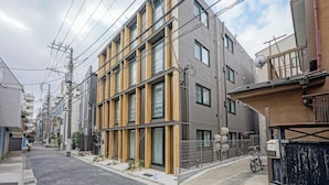 Een modern meerlaags woongebouw met een gevel van hout en beton, meerdere ramen en zichtbare elektriciteitskabels.