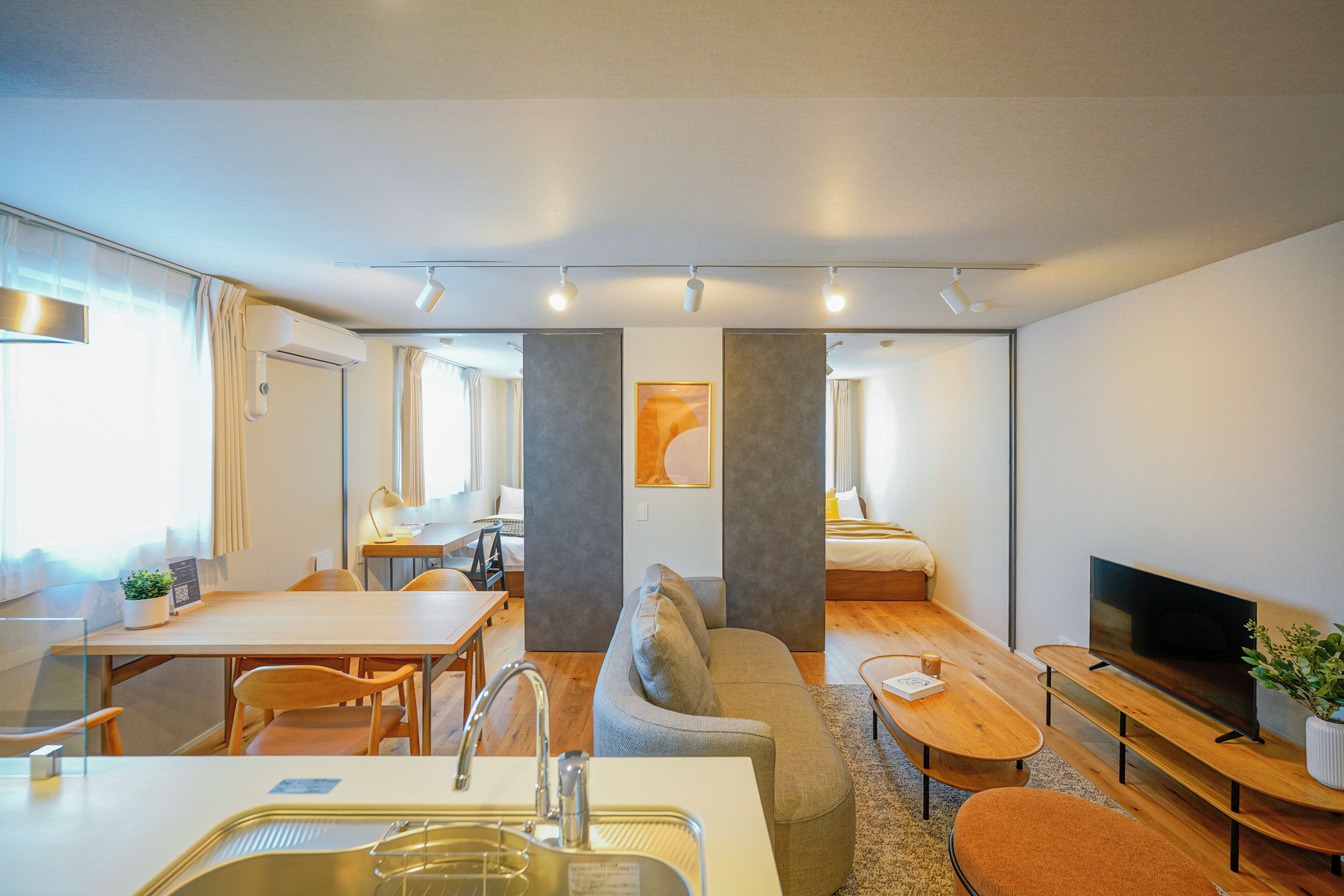Une chambre d’hôtel moderne équipée d’une kitchenette, d’un canapé, d’une table à manger et d’un téléviseur.