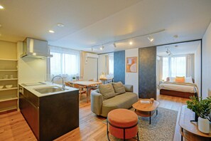 A modern hotel room with a kitchenette, a sofa, a dining area, and a separate bedroom. - Dash Living Nezu (Bunkyo-ku)
