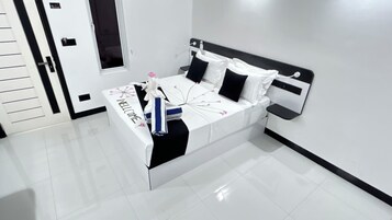 Habitación de hotel moderna con una cama bien hecha, una mesita de noche y un televisor montado en la pared.