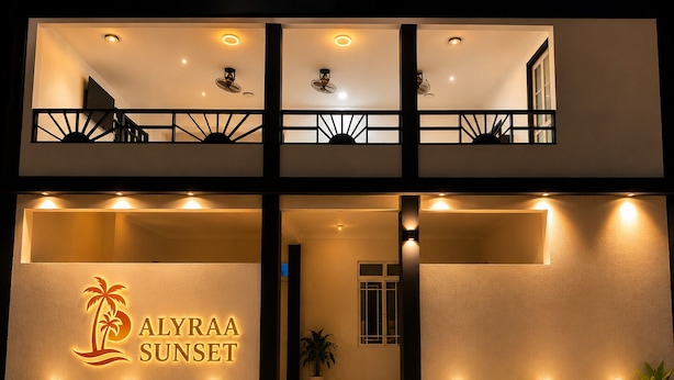 A two-story hotel with a balcony on the upper floor, a sign reading 'ALYRAA SUNSET,' and potted plants along the entrance. - Alyraa sunsets  (Mathiveri)