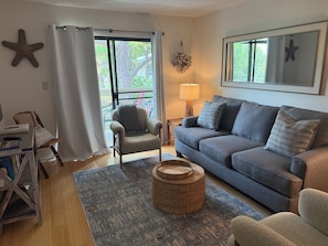 A living room with a grey sofa, armchairs, a coffee table, a starfish decoration, and a window with curtains. - Fiddler's Cove - 2 Pool -Tennis - Hot Tub - Gym - Walk to the Beach! (Hilton Head Island)