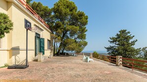 Un edificio con un canestro da basket, un'area pavimentata e vista sul mare.