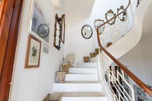 A staircase with white steps, a wooden handrail, and various decorative items including framed pictures and mirrors. - Villino alla Croce by Wonderful Italy (Ostuni)