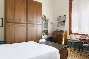 A hotel room with a large wooden wardrobe, a desk with a telephone, two chairs, and a bed with a white bedspread. - Villino alla Croce by Wonderful Italy (Ostuni)