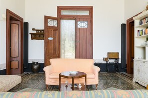 A traditional room with a sofa, a small table, a radiator, a bookshelf, and a door with a glass panel. - Villino alla Croce by Wonderful Italy (Ostuni)