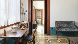Una stanza con un tavolo da pranzo in legno, sedie, un divano e un pavimento decorato.