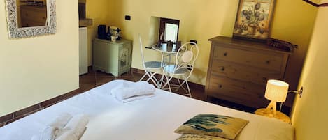 Una habitación de hotel con cama, escritorio, silla, cómoda y lámpara.