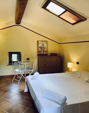 A bedroom with a bed, a desk, a chair, a dresser, and a painting on the wall.