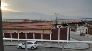 Una calle residencial con casas, un coche blanco y una vista despejada de montañas a lo lejos.