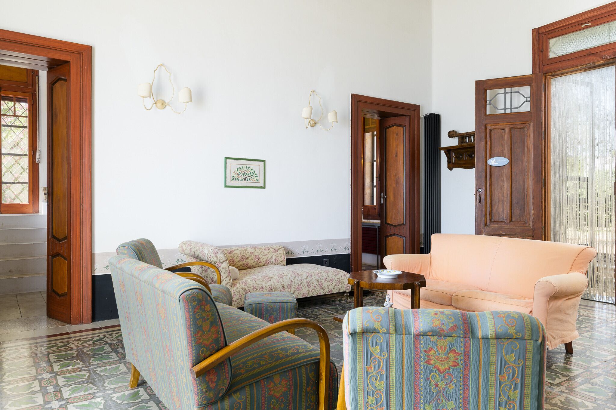 A living room with a sofa, armchairs, a coffee table, and a door with a sign.