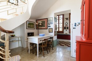 A kitchen with a white table, wooden chairs, a blue bowl, and various framed pictures on the wall. - Villino Alla Croce by Wonderful Italy (Ostuni)