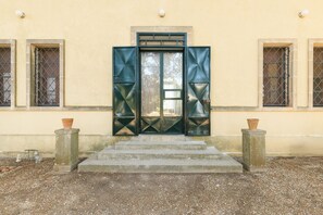 A building entrance with a set of concrete steps leading up to a door with geometric patterns. - Villino Alla Croce by Wonderful Italy (Ostuni)