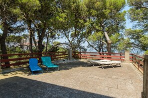 An outdoor seating area with a gravel surface, surrounded by trees and a red railing. - Villino Alla Croce by Wonderful Italy (Ostuni)