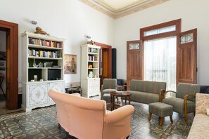 A living room with a large white bookshelf, two armchairs, a sofa, and a television. - Villino Alla Croce by Wonderful Italy (Ostuni)