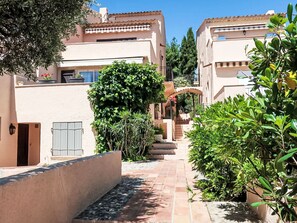 A narrow courtyard with a tiled pathway, surrounded by buildings with beige walls and terracotta roofs. - Village de Silhouette by Interhome (Grimaud)