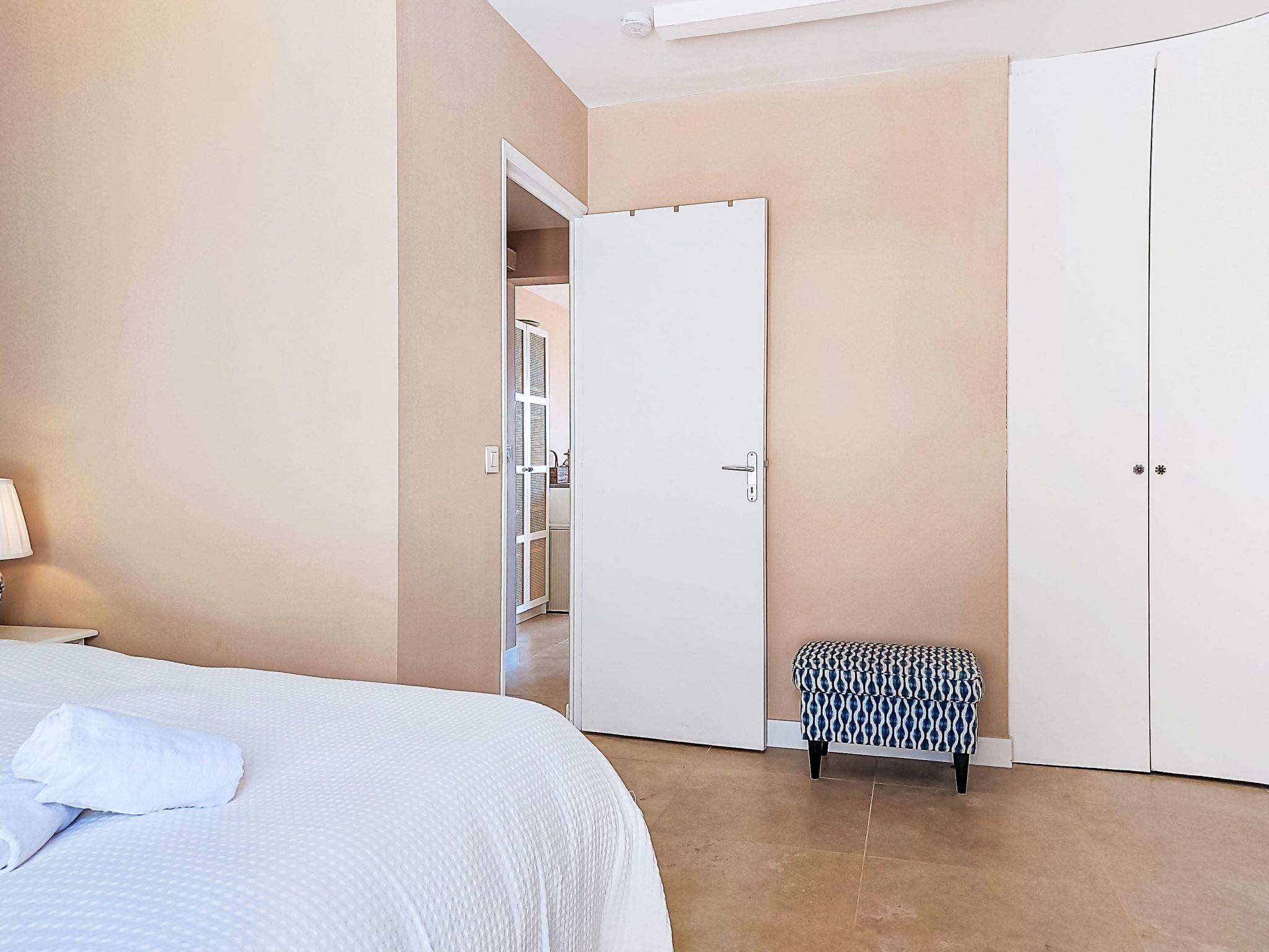 A bedroom with a bed, a small bench, and a closet.
