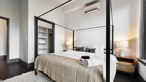 Um quarto moderno com uma cama de dossel, um closet espaçoso e uma mesa de cabeceira com abajur.