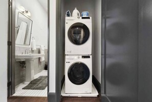 A laundry room with two stacked washing machines, a sink, and a mirror. - Stylish Downtown 2BR | Walkable to NFL (Pittsburgh)