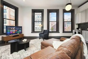 Bright loft-style living room with big windows, city views, and smart TV - Stylish Downtown 2BR | Walkable to NFL (Pittsburgh)