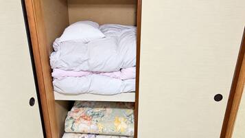 A wardrobe with a bed at the bottom and a shelf above with folded bedding.