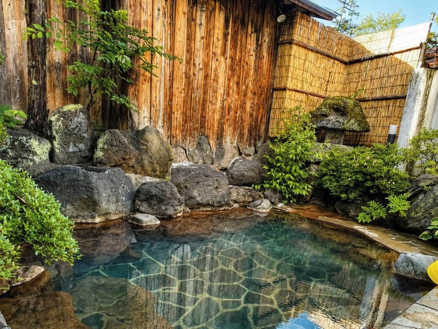 Un jardín con un elemento acuático, rodeado de rocas y follaje.