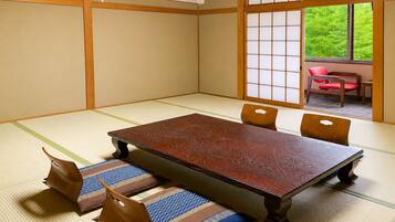A tatami room with a low wooden table, cushions, and a sliding door leading to an outdoor area.