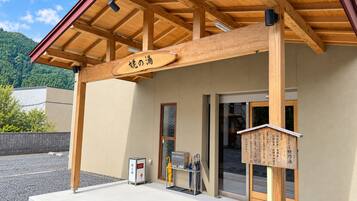 Un edificio con estructura de madera, un letrero con caracteres japoneses, un pequeño quiosco y una puerta de acceso.