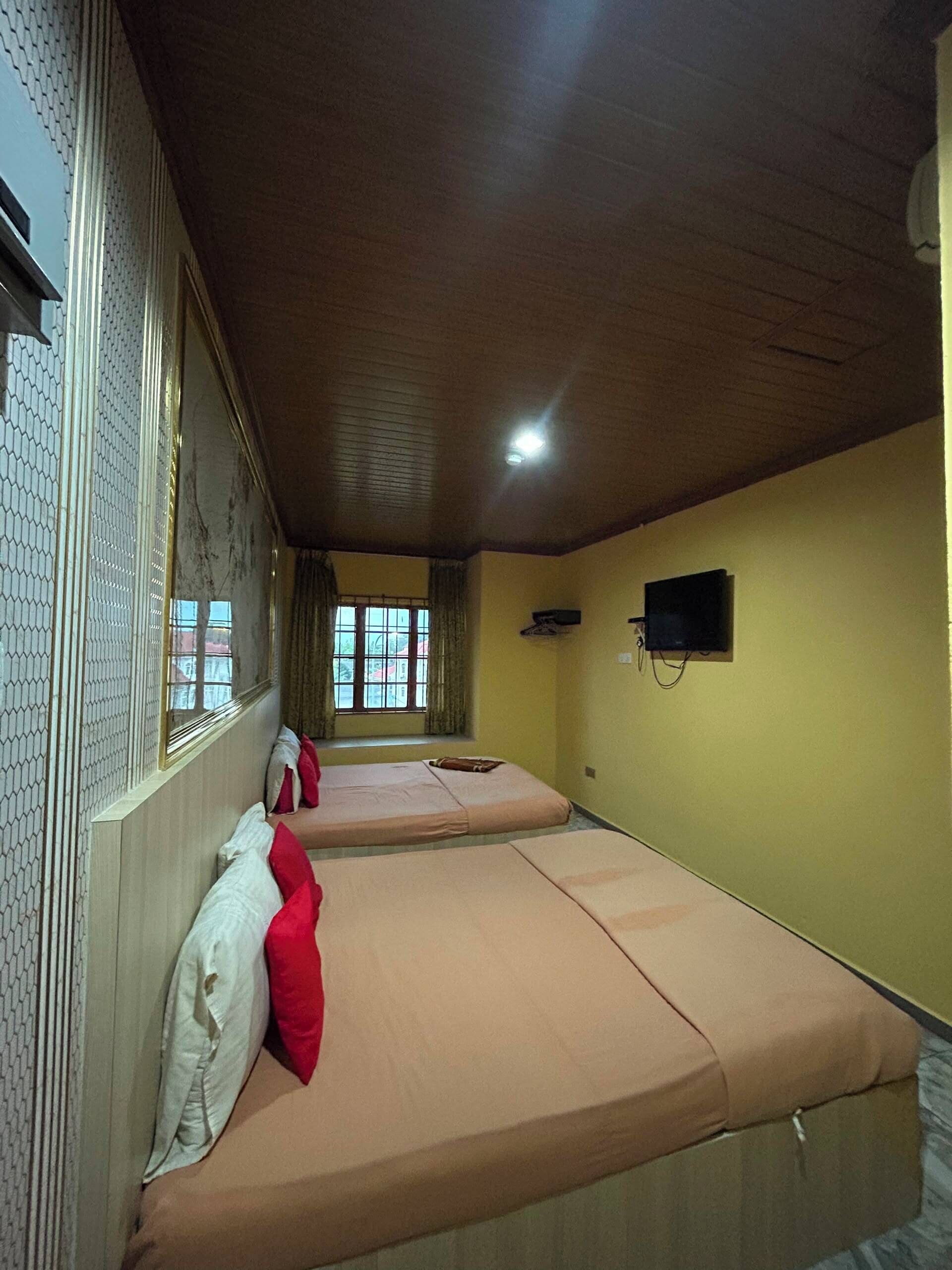 Een kamer met twee bedden, een televisie en een raam met gordijnen.