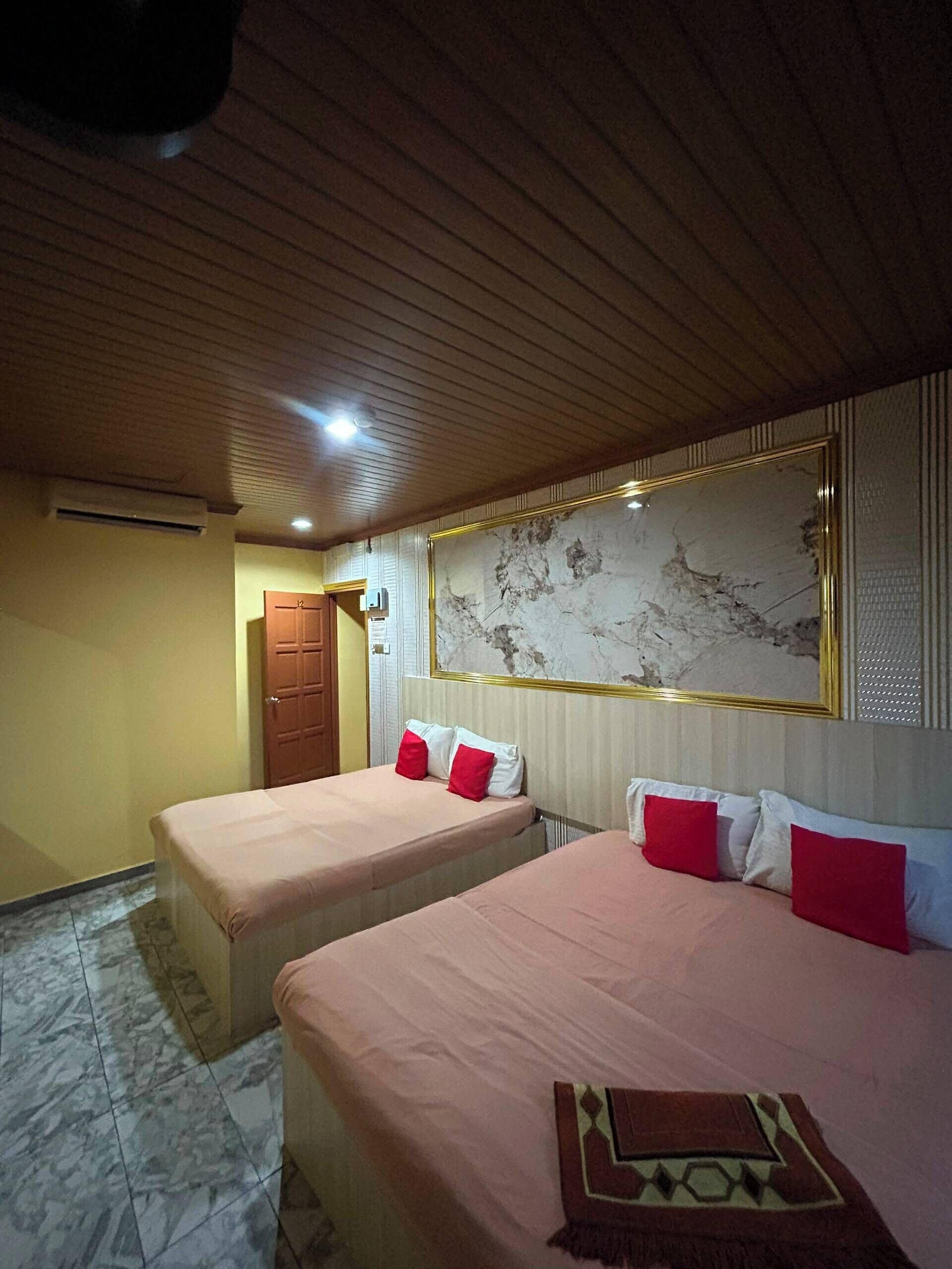 A hotel room with two beds, a wooden ceiling, a marble floor, and a large painting on the wall.