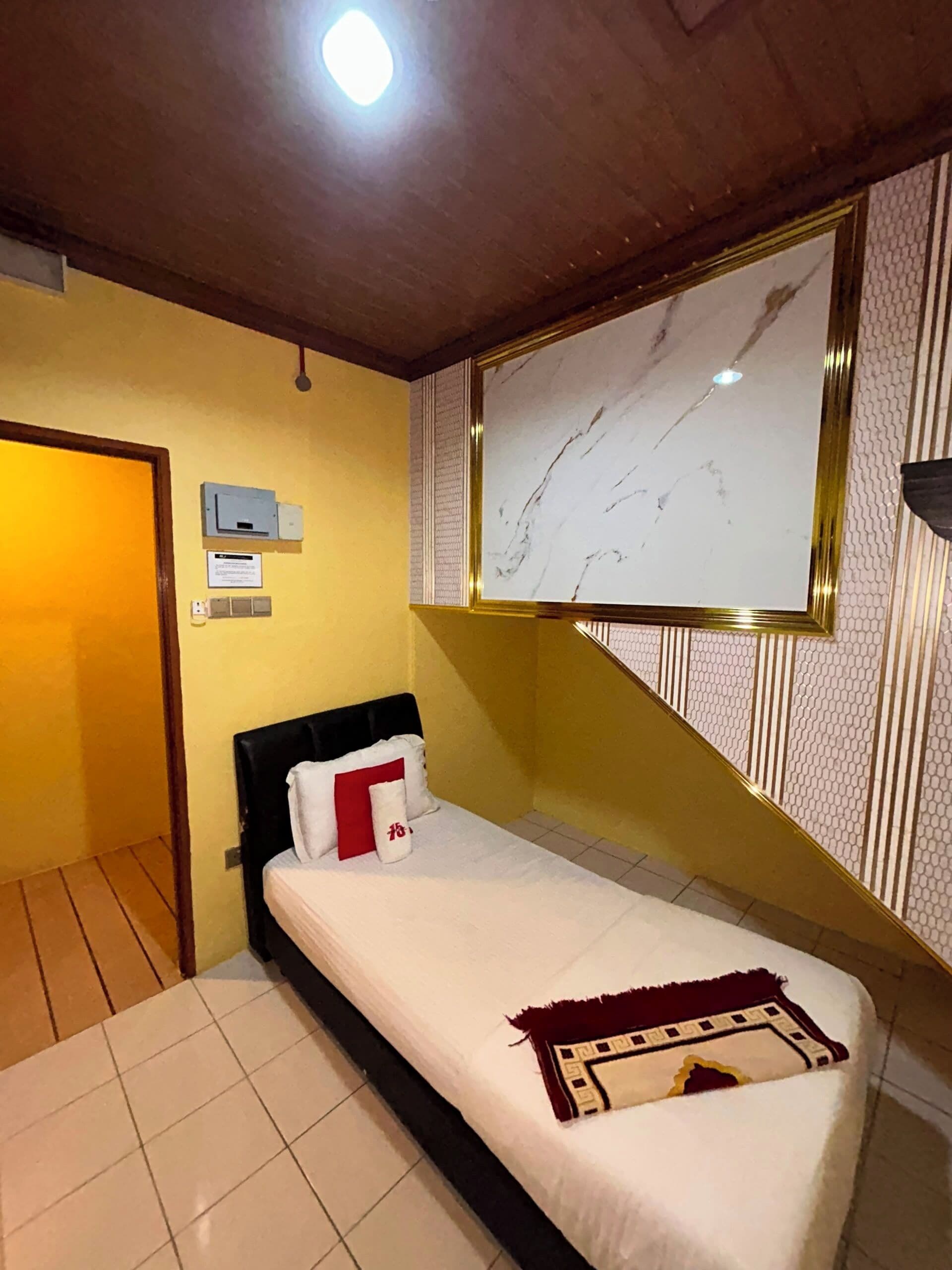 Een kamer met een bed, een televisie aan de muur, een deur en een lamp.